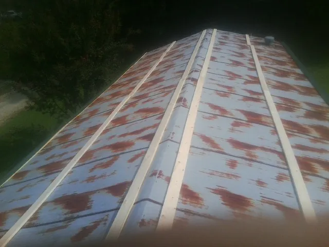 Rusted metal roof panels with new wood purlins before replacement — Storm Damage Roof Repair in Como by Roofing Brothers