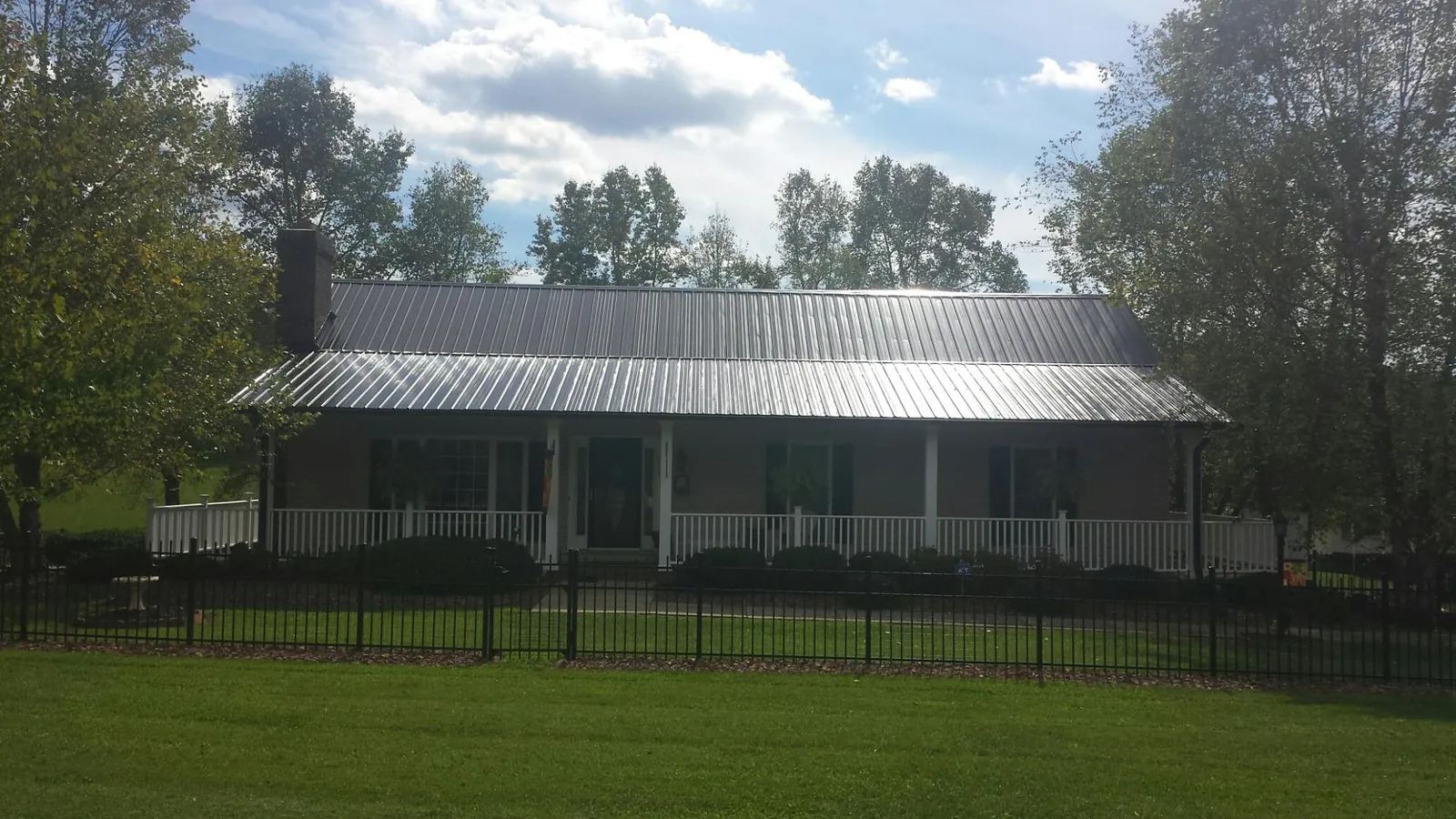 Gray metal roof on a brick ranch with a full width front porch — Gutter Guard Installation work by our crew in Como